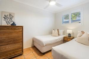 a bedroom with two beds and a dresser and a window at Absolute Beachfront Apartment 2B in Lennox Head