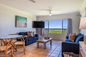 a living room with a blue couch and a table at Absolute Beachfront Apartment 2B in Lennox Head +16 photos