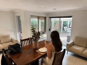 a woman sitting at a table in a living room at Canberra Stylish Escape in Harrison