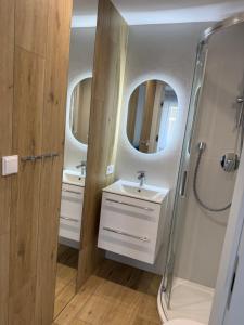 a bathroom with two sinks and a shower at Apartamenty Solano - wybrane z widokiem na morze in Rowy +81 photos