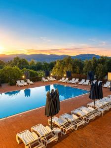 a resort pool with lounge chairs and umbrellas at Agriturismo L'Antica Vigna in Randazzo