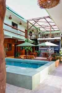 ein Schwimmbad mit Tischen und Sonnenschirmen neben einem Gebäude in der Unterkunft Hippie Fish Hostal in Holbox