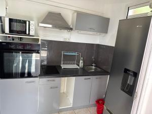 a kitchen with white cabinets and a black counter top at Le Pavillon Ananas in Gros-Morne