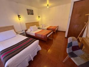 a room with two beds and a table and a chair at Hotel Turi Atacama in San Pedro de Atacama