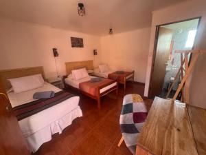a hotel room with two beds and a table at Hotel Turi Atacama in San Pedro de Atacama +8 photos
