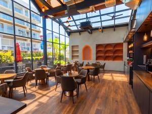 a restaurant with tables and chairs and large windows at Imperial Swiss Garden Dhaka in Dhaka