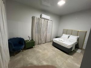 a bedroom with a bed and a blue chair at Casa Quinta Locha in Ciudad del Este +12 photos