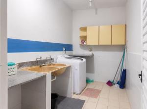 a small bathroom with a sink and a washing machine at Sossai Hostel in Vitória