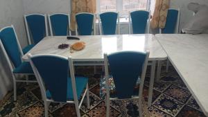 a table with blue chairs and a plate of food on it at Mamyr Guest House in Sary-Mogul