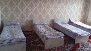 three beds in a room with a wall at Mamyr Guest House in Sary-Mogul