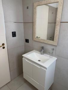 a white bathroom with a sink and a mirror at Aura Residence in Comodoro Rivadavia