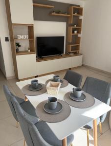 a dining room with a white table with blue cups and chairs at Aura Residence in Comodoro Rivadavia