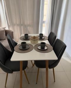 a table with black chairs and a white table with two cups on it at Aura Residence in Comodoro Rivadavia