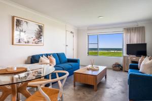 a living room with a blue couch and a table at Absolute Beachfront Apartment 3B in Lennox Head