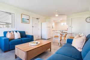 a living room with two blue couches and a table at Absolute Beachfront Apartment 3B in Lennox Head