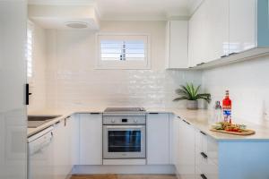 a white kitchen with white cabinets and a window at Absolute Beachfront Apartment 3B in Lennox Head +12 photos