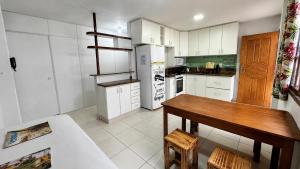 a kitchen with white cabinets and a wooden table at Sossai Hostel in Vitória