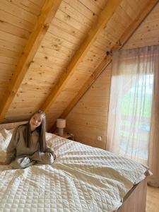 a woman sitting on a bed in a attic at Camp Birch Forest in Pljevlja