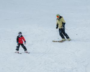 a man and a child skiing down a snow covered slope at Altitude Apartment 2 in Baw Baw Village