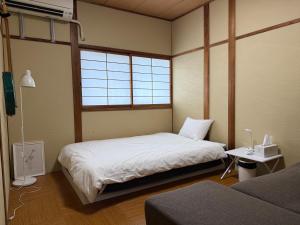 a bedroom with two beds and a window at 民泊利休 in Sakai