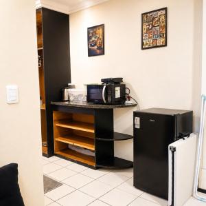 a kitchen with a counter with a microwave and a refrigerator at Quarto triplo em Petrópolis in Natal
