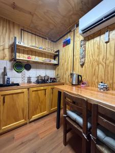 a kitchen with wooden cabinets and a wooden table at El Refugio Container in Futaleufú