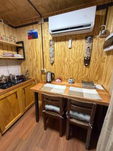 a kitchen with a wooden table with two chairs at El Refugio Container in Futaleufú +1 photo