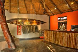 a woman standing at a bar in a room with orange walls at Thamalakane River Lodge in Maun