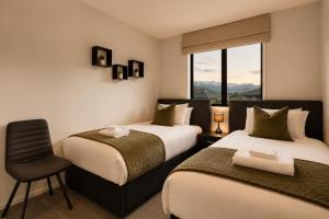 a bedroom with two beds and a chair and a window at Modern Mountain View Retreat, 2 Bedroom Stay in Frankton