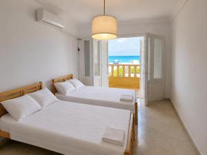 two beds in a bedroom with a view of the ocean at فيلا غرناطه الساحل الشمالي in Dawwār al Ḩajj Aḩmad