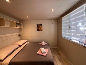 a small bedroom with a bed and a window at Mobile Home Ana Mia in Biograd na Moru