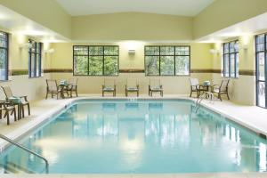 una piscina con sillas, mesas y ventanas en Courtyard by Marriott Lake George, en Lake George