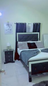 a bedroom with a large bed and a night stand at Escape casa Ja in Portmore