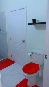 a bathroom with a toilet with a red rug at Escape casa Ja in Portmore