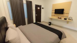 a bedroom with a large bed and a television at Aisyi Tower Klaten in Klaten