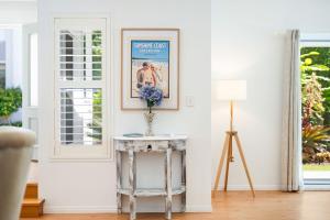 a living room with a table and a picture on the wall at Winders Beach House in Marcoola +24 photos
