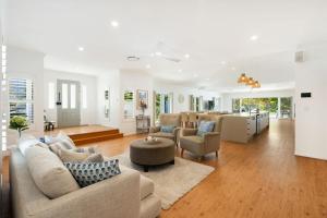 a living room with couches and a table and a kitchen at Winders Beach House in Marcoola