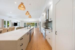 a kitchen with white cabinets and a white counter top at Winders Beach House in Marcoola