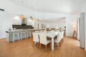 a dining room and kitchen with a white table and chairs at Winders Beach House in Marcoola