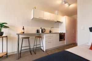 a kitchen with white cabinets and bar stools in a bedroom at Lake & Mountain Views, Close to Shops & Dining in Queenstown +5 photos