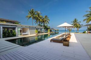 an infinity pool with chairs and an umbrella next to a house at Villa Amarelo in Ban Han Pa To