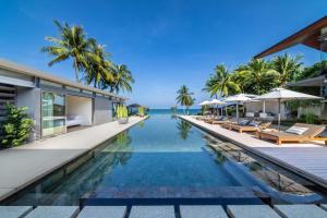 an infinity pool at a resort with chairs and umbrellas at Villa Amarelo in Ban Han Pa To
