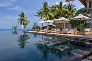 a pool at a resort with chairs and umbrellas at Villa Amarelo in Ban Han Pa To