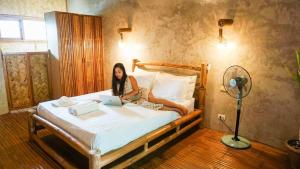 a woman sitting on a bed with a laptop at Happiness Native Villa in El Nido