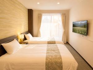 two beds in a hotel room with a window at Sugamo Winco Residence 新宿まで電車14分 巣鴨駅徒歩3分 光wifi エレベーター 商店街徒歩4分 in Tokyo