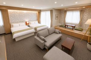 a hotel room with two beds and a couch at Sugamo Winco Residence 新宿まで電車14分 巣鴨駅徒歩3分 光wifi エレベーター 商店街徒歩4分 in Tokyo