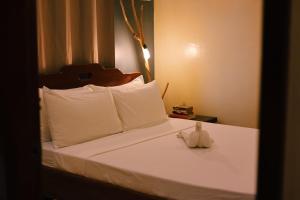 a bed with white pillows and a stuffed animal on it at Happiness Beach Resort Siargao in General Luna