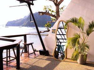 a chair sitting next to a table with a view of the water at Outpost Beach Hostel in El Nido