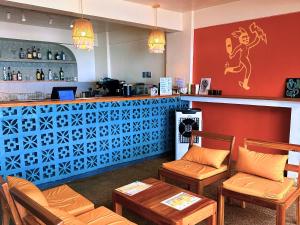 a restaurant with a bar with orange chairs and a counter at Outpost Beach Hostel in El Nido