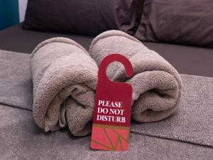a towel on a bed with a sign on it at Outpost Beach Hostel in El Nido